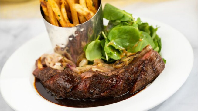 A plate of Steak Frites and a small salad from Be Our Guest