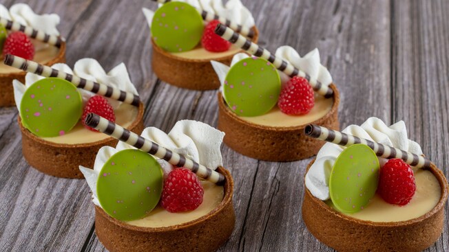 Six small key lime pies topped with cream and fruit