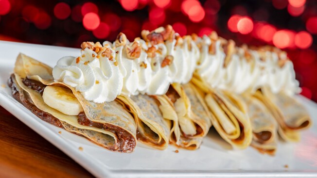 A plate of crepes topped with whipped cream, bananas and nuts, at Chef Mickey’s
