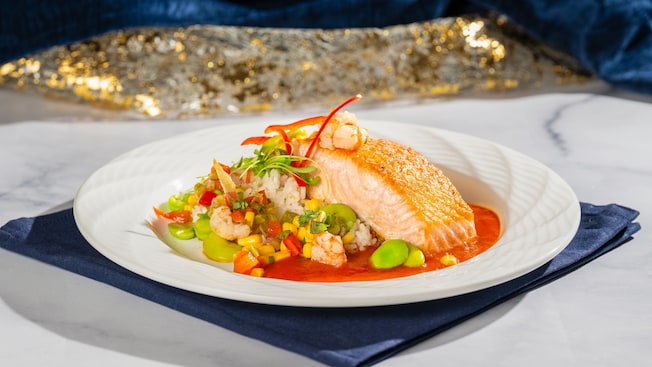Un filete de pescado servido encima de arroz y vegetales con salsa