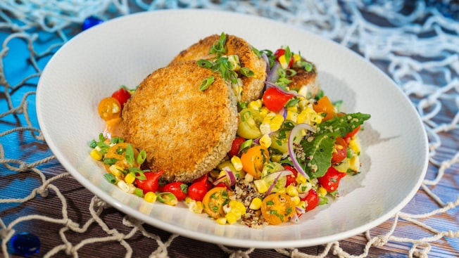 A bowl of Coastal Palm Cakes with hearts of palm, quinoa, kale, pearl peppers, tomatoes, red onions and corn
