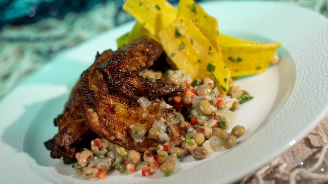 A plate of Caribbean style chicken with rice, black eyed peas and crispy plantains