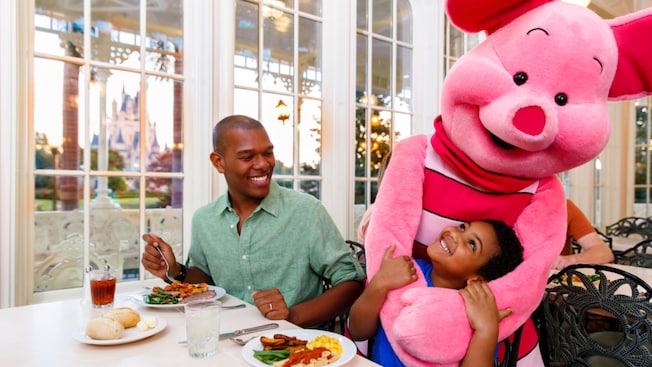 Piglet hugging a child sitting at a table in The Crystal Palace