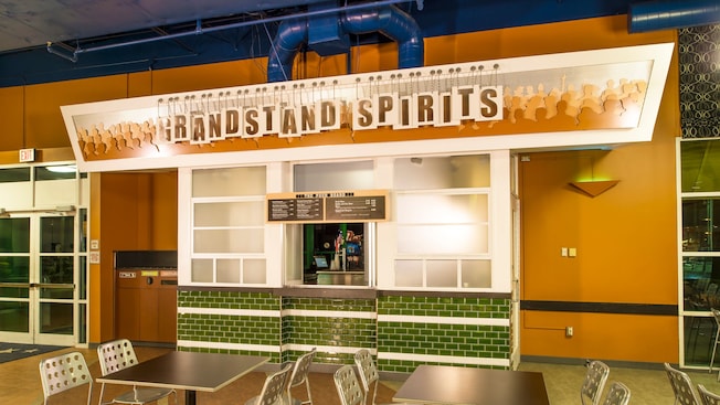 Tables and chairs arranged near a food stand with the sign ‘Grandstand Spirits’