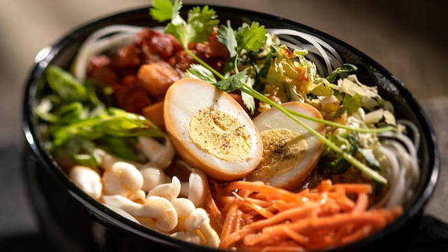 A bowl filled with meat and vegetables topped with hard boiled eggs