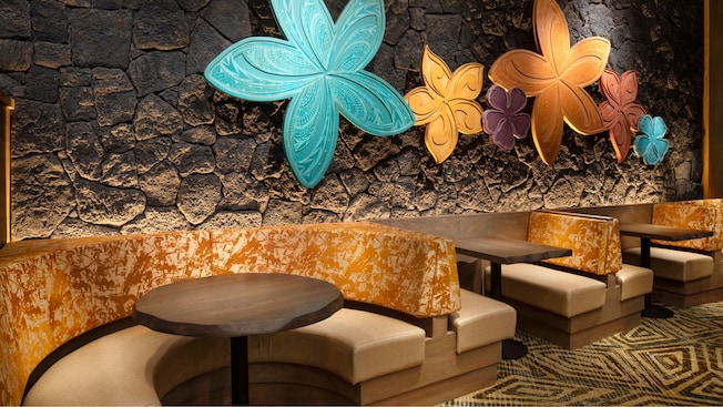 Plumeria flower wood carvings on a wall next to a row of restaurant booths