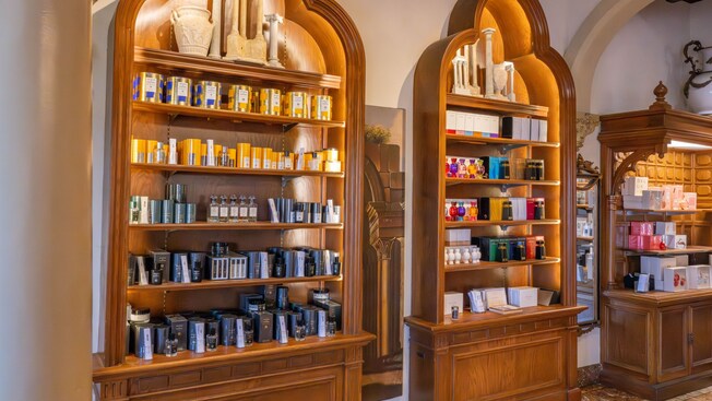 Three wooden display shelves holding fragrances and personal care items inside of Il Bel Cristallo at Epcot