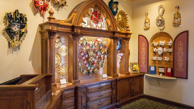 A section of Il Bel Cristallo at Epcot with carved wooden cabinets displaying Venetian carnival masks