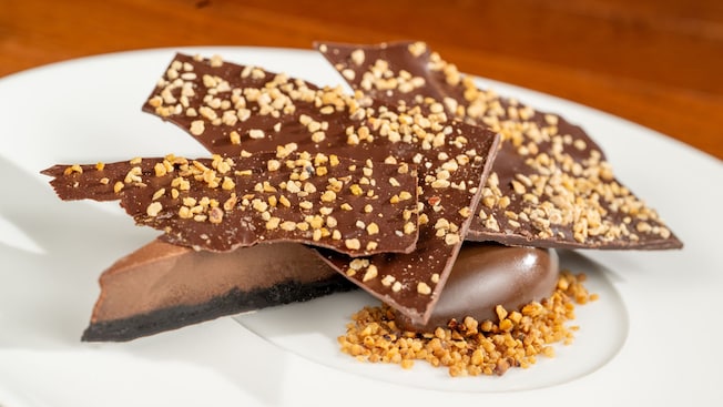 Un gâteau au fromage au chocolat décadent garni de morceaux de noix croquantes dans une assiette du Cellier Steakhouse