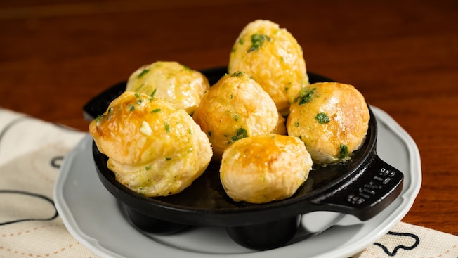 Six escargots moelleux en croûte servis dans une poêle en fonte sur une assiette du Cellier Steakhouse