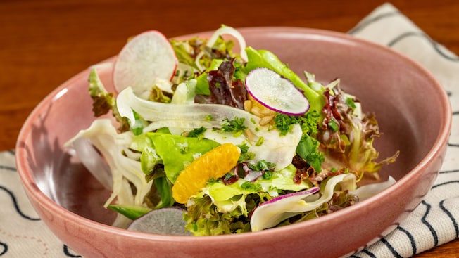 Une salade de verdures avec du fenouil émincé, des agrumes de la Floride, du radis, une vinaigrette au citron et des graines de tournesol dans un bol du restaurant Le Cellier Steakhouse