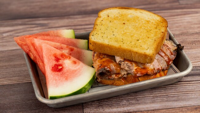 Um sanduíche fatiado de peito bovino à moda do Texas com pedaços de melancia para acompanhar