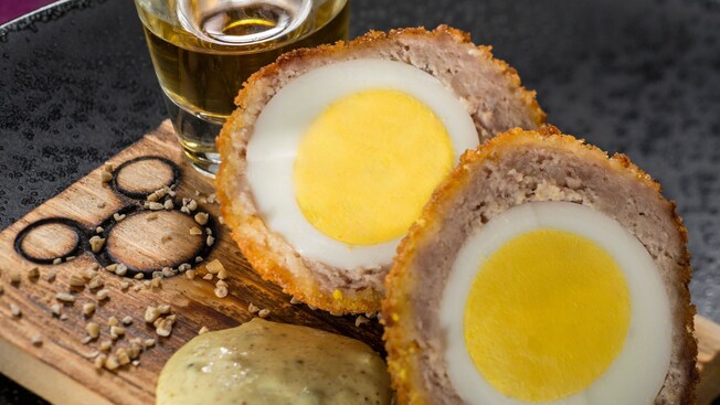 A Scotch Egg with mustard sauce and a glass of beer from Rose and Crown Dining Room at Epcot