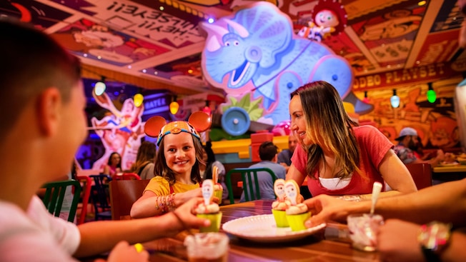 Una familia toma cupcakes de un plato en un restaurante decorado con Personajes de Toy Story