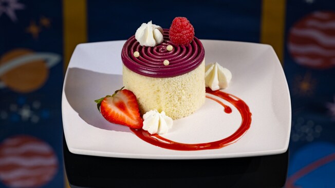 A cake topped with icing, whipped cream and a medley of berries