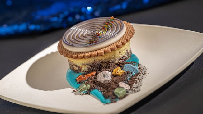 Um cheesecake de brownie de caramelo coberto com panna cotta de Oreo, calda de baunilha, pedras de chocolate e farofinha de Oreo