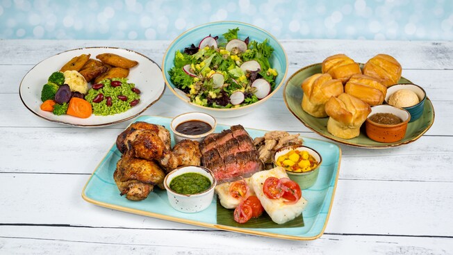 A table featuring grilled chicken, steak, fish, pork, veggies and rice with plantains, salad and dinner rolls from Sebastian's Bistro