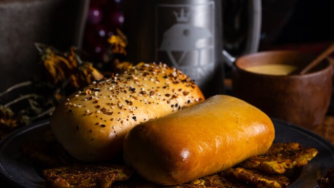 Panecillos de levadura caseros conocidos como Coffyns en una bandeja cerca de un tazón y una taza de metal en Six Ravens