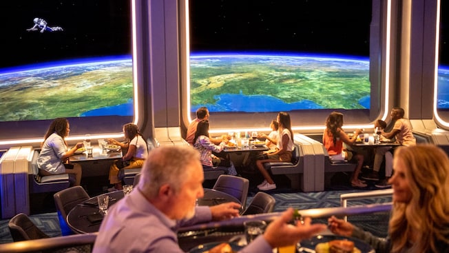 Visitors to Space 220 Restaurant eat while watching an astronaut float above Earth