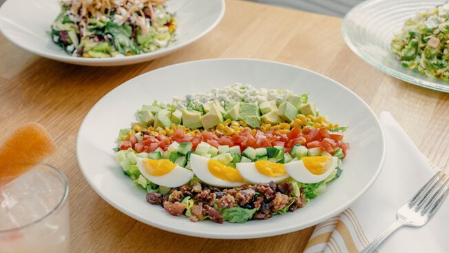 Several dishes, including 2 different salads, chips and guacamole, and a large cookie