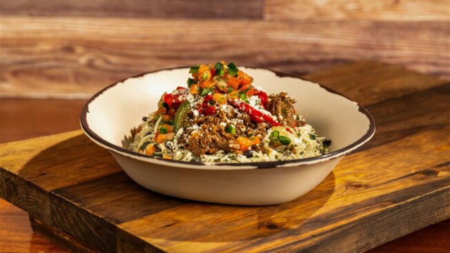 A Barbacoa Beef Bowl from Sunshine Seasons with braised meat, cilantro-lime rice, black beans, onions, peppers, cotija, and pico de gallo
