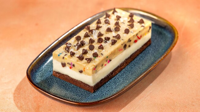 A layered cookie dough dessert bar on a plate