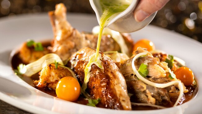 A woman pours sauce over chicken and dumplings