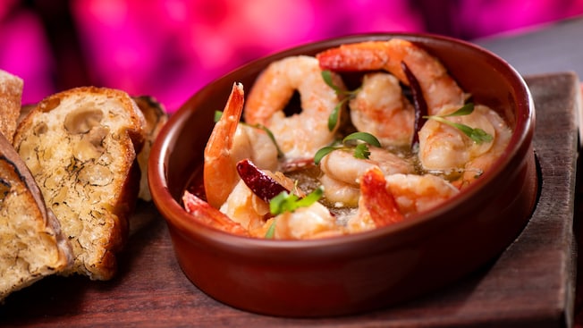 Un tazón de camarones, aceite de oliva y mantequilla de hierbas con pan tostado de Toledo Tapas, Steak & Seafood