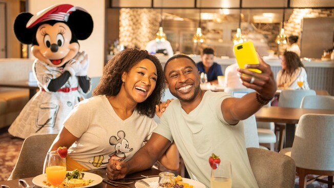 Minnie interacts with a family as they dine at Topolino’s Terrace, Flavors of the Riviera