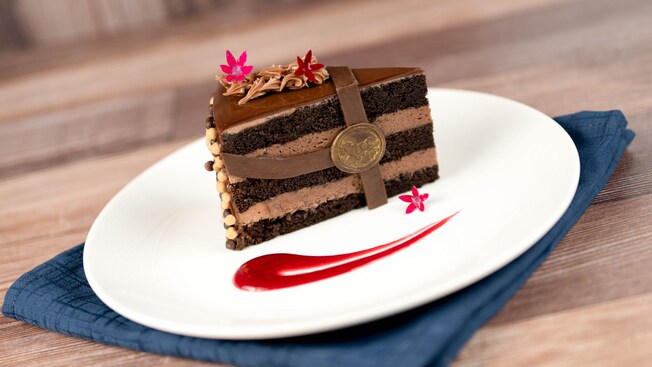 A slice of the Signature Chocolate Cake from The Turf Club Bar & Grill with a horse racing themed chocolate decoration and edible flowers