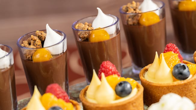 Vasitos de mousse de chocolate y tartas de fruta cubiertas con bayas frescas