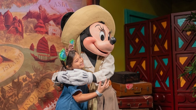 Visitante joven abrazando a Minnie Mouse en Adventurers Outpost, en Disney's Animal Kingdom Theme Park