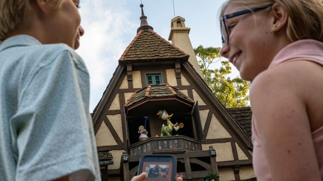 2 Guests hold a cellphone to make a Donald Duck figurine to appear during the DuckTales World Showcase Adventure