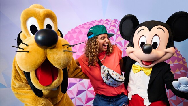 Un Visitante posando para una foto con Pluto y Mickey Mouse en el Disney Visa photo spot en Epcot