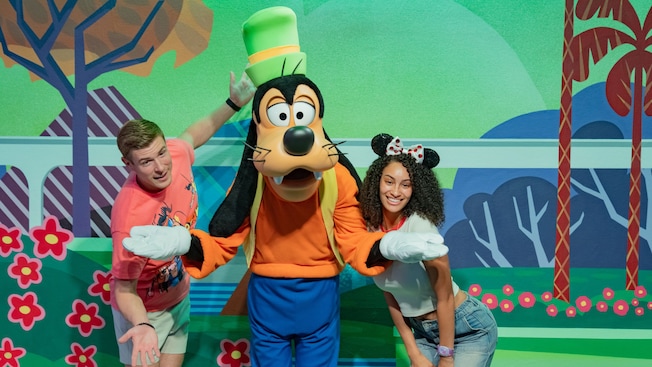 Dois jovens Visitantes posando para uma foto com o Goofy