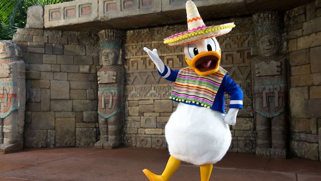 Donald Duck wearing a poncho and sombrero in front of stone sculptures at the Mexico Pavilion in Epcot