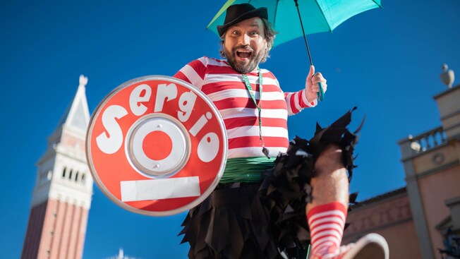 Sergio, holding an umbrella, performs a comedy mime routine at the Italy Pavilion
