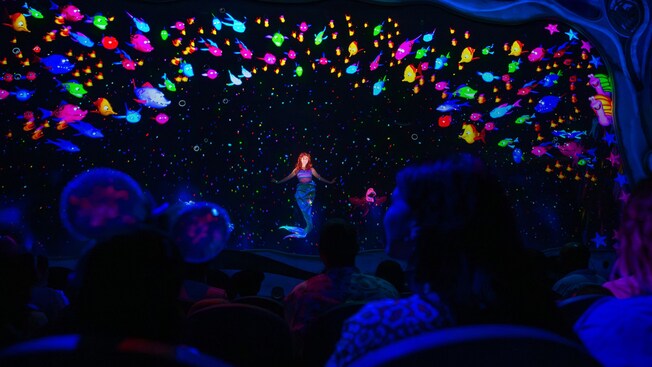 Ariel swims in the depth of the ocean, surrounded by a vast array of fish and sea creatures