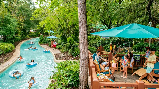 Guests floating down Cross Country Creek as families dine on a nearby deck at Disney’s Blizzard Beach water park