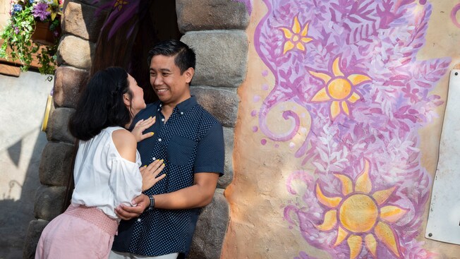 A man and a woman hold each other near a Tangled themed mural
