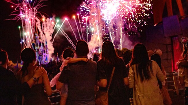 A crowd watching fireworks burst above Cinderella Castle at Magic Kingdom park