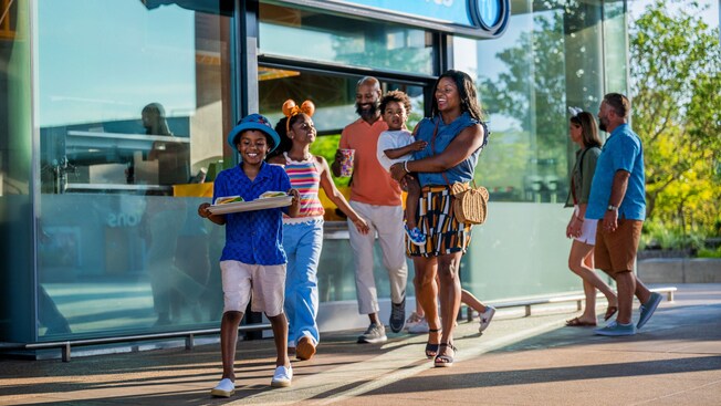 A young family of 5 departing an outdoor ‘Festival Favorites’ dining area with a tray of food