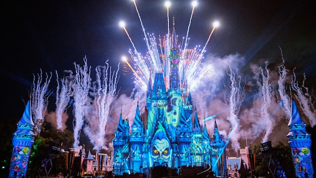 Dazzling fireworks light up the night sky surrounding an illuminated Cinderella Castle as Jack Skellington spreads his arms open on stage