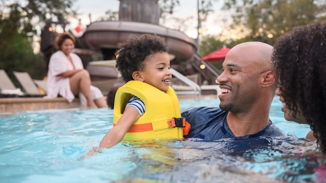 Dos padres sostienen a su hijo pequeño en la piscina de Disney’s Fort Wilderness Resort