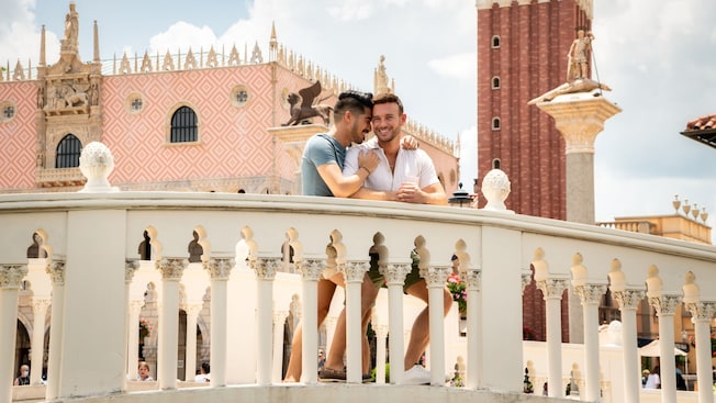 A smiling couple poses on a bridge in the EPCOT World Showcase Italy Pavilion at Walt Disney World Resort