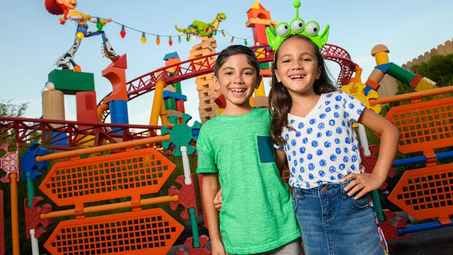 A young boy and girl smiling for a photo together in Toy Story Land near the Slinky Dog Dash coaster