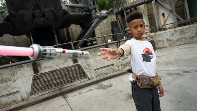 A boy reaching toward a lightsaber in Star Wars Galaxy's Edge