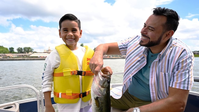 A father and son hold a fish on a boat on Seven Seas Lagoon