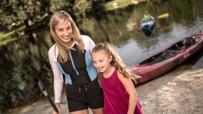 Mother and daughter posing and smiling in front of a kayak at Disney's Fort Wilderness Resort and Campground