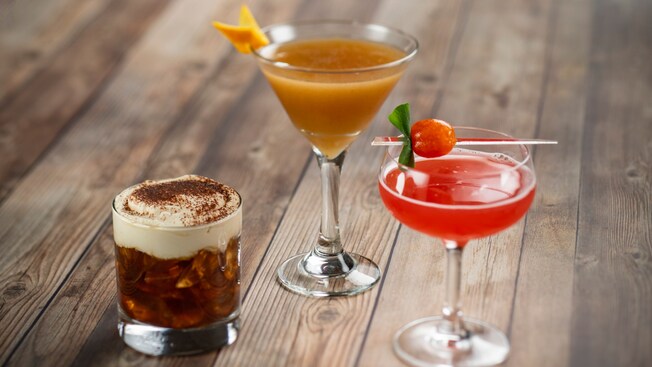 Three cocktails arranged on a wood table